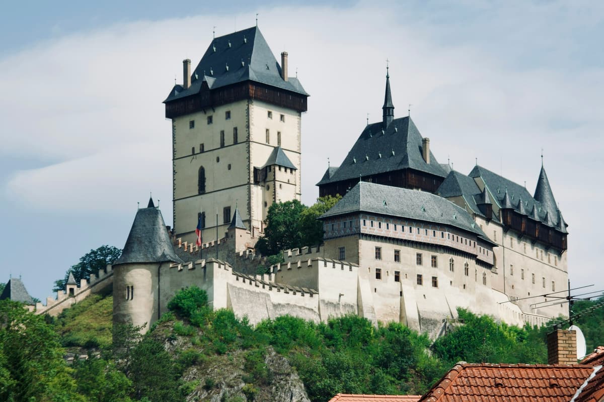 El Castillo de Karlštejn se alza sobre las colinas boscosas de Bohemia, al suroeste de Praga: una escalonada fortaleza gótica de muros de piedra clara y tejados rojos coronada por la Gran Torre.